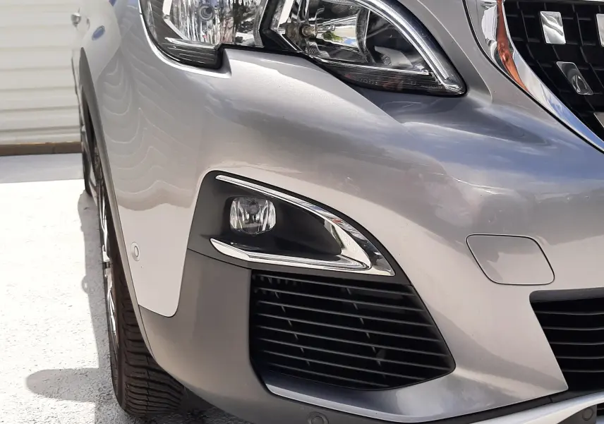 Gros plan sur l'avant droit gris d'un Peugeot 3008 2020, mettant en valeur le phare et la calandre chromée.