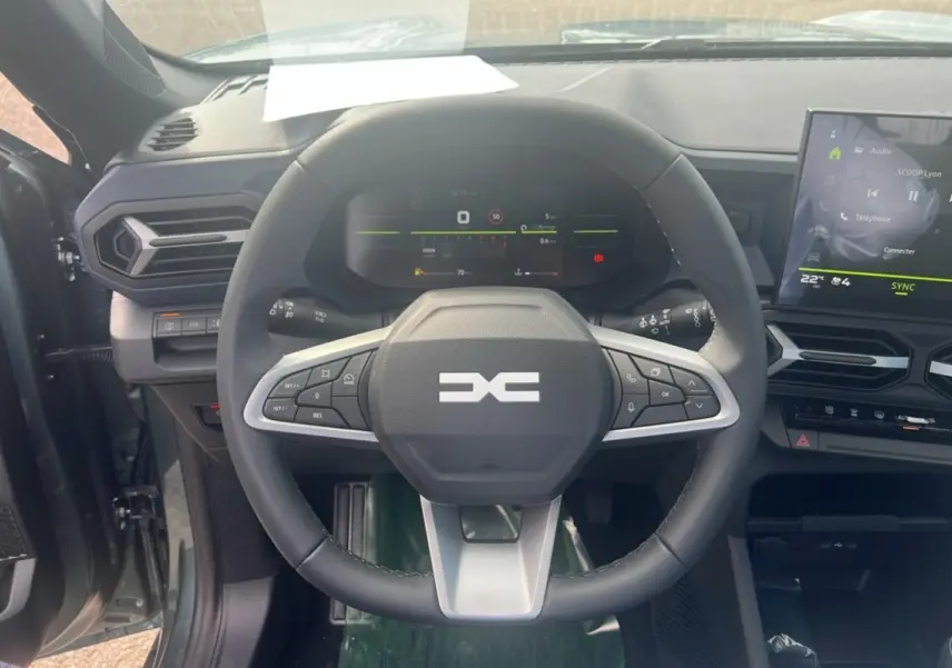 Vue intérieure centrée sur le volant multifonction du Dacia Bigster 2025 avec tableau de bord digital et écran tactile.