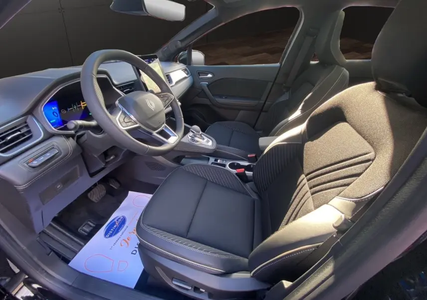 Intérieur avant droit de la Renault Symbioz Iconic E-Tech Hybrid 2025 avec sièges noirs et tableau de bord digital.