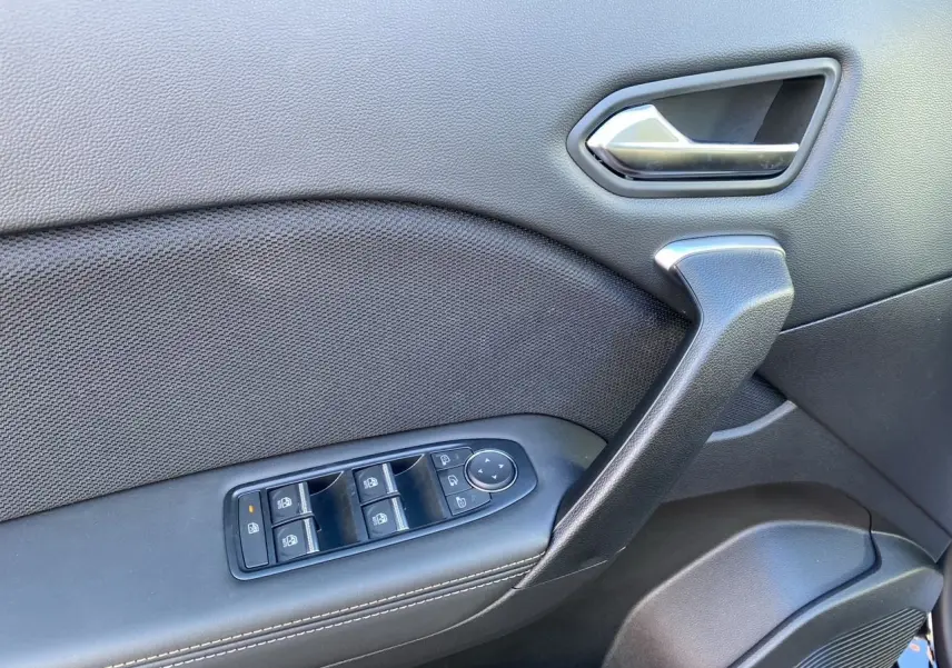 Détail de la porte côté gauche de la Renault Symbioz Iconic E-Tech Hybrid noire, avec commandes des vitres et poignée argentée.