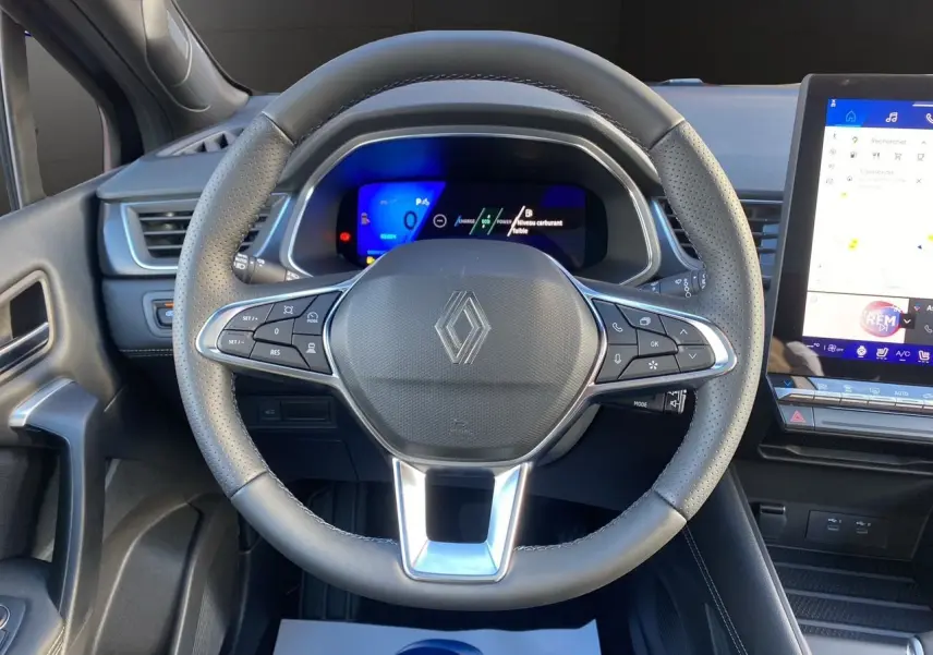 Vue rapprochée du volant noir perforé et du tableau de bord numérique du Renault Symbioz Iconic E-Tech Hybrid 2025.