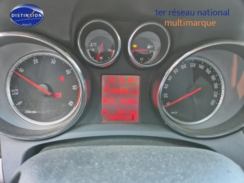 Tableau de bord de l'Opel Mokka gris Astéroïde, affichage rouge des compteurs et alertes visibles.