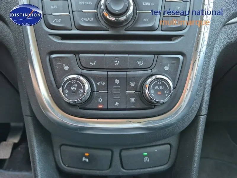 Vue rapprochée de la console centrale du Opel Mokka 2016, boutons de climatisation et commandes chauffantes visibles.