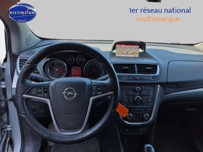 Intérieur avant d'un Opel Mokka gris, vue centrée sur le volant cuir multifonction et tableau de bord avec écran GPS intégré.