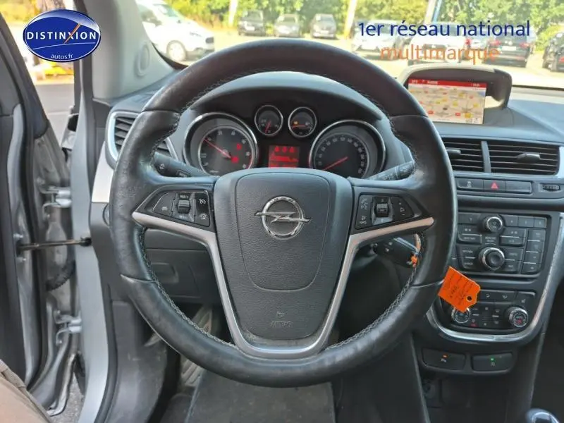 Vue intérieure centrée sur le volant cuir multifonction d'une Opel Mokka gris astéroïde avec tableau de bord et écran GPS visible