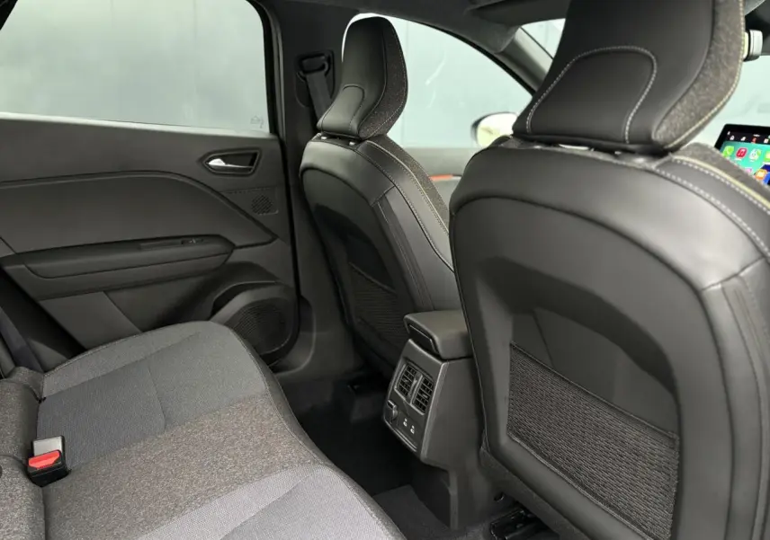 Vue intérieure arrière du Renault Captur 2025 montrant les sièges en tissu gris et la console centrale avec aérateurs et ports USB.
