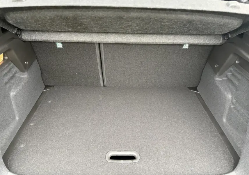 Vue intérieure du coffre spacieux et couvert du Renault Captur 2025, version hybride, avec revêtement gris foncé.