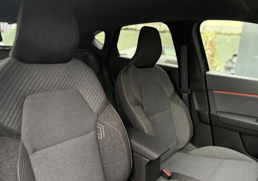 Vue intérieure des sièges avant gris avec coutures contrastantes et accoudoir central du Renault Captur 2025 noir étoile.