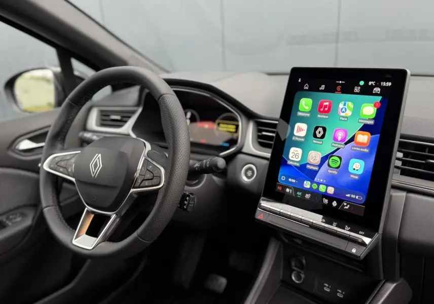 Vue intérieure côté conducteur du Renault Captur 2025, volant noir avec logo Renault et grand écran tactile central allumé.