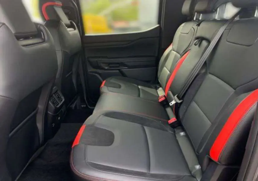 Vue latérale des sièges arrière noirs avec surpiqûres rouges du Ford Ranger Raptor V6 2025, intérieur spacieux et moderne.