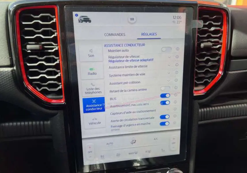 Écran tactile central du Ford Ranger Raptor 2025 avec réglages d'assistance conducteur, entouré de grilles d'aération rouges.