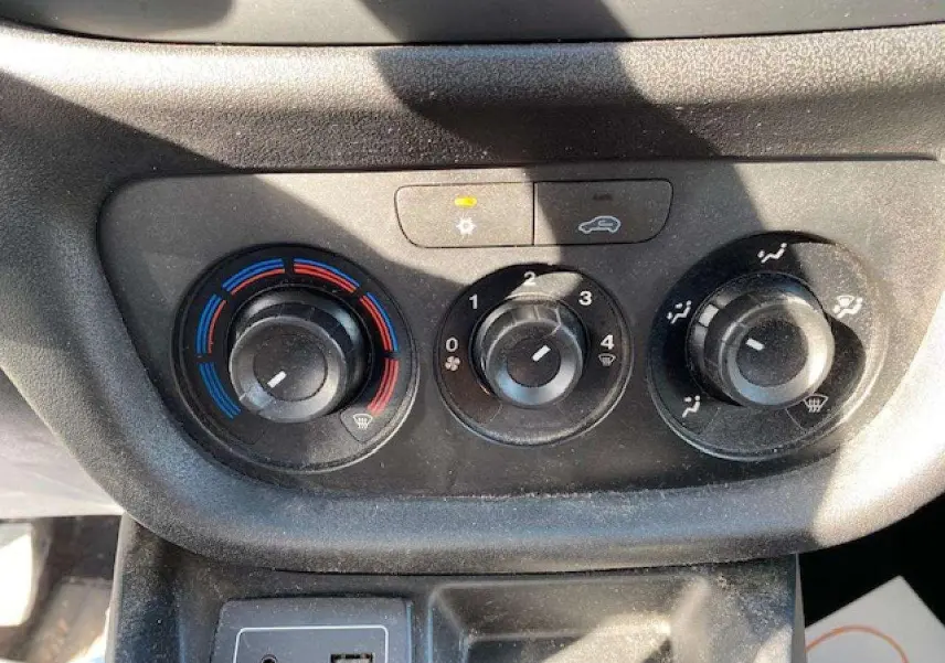 Gros plan sur les commandes de climatisation manuelle et la prise USB du tableau de bord du Fiat Doblo blanc de 2017.