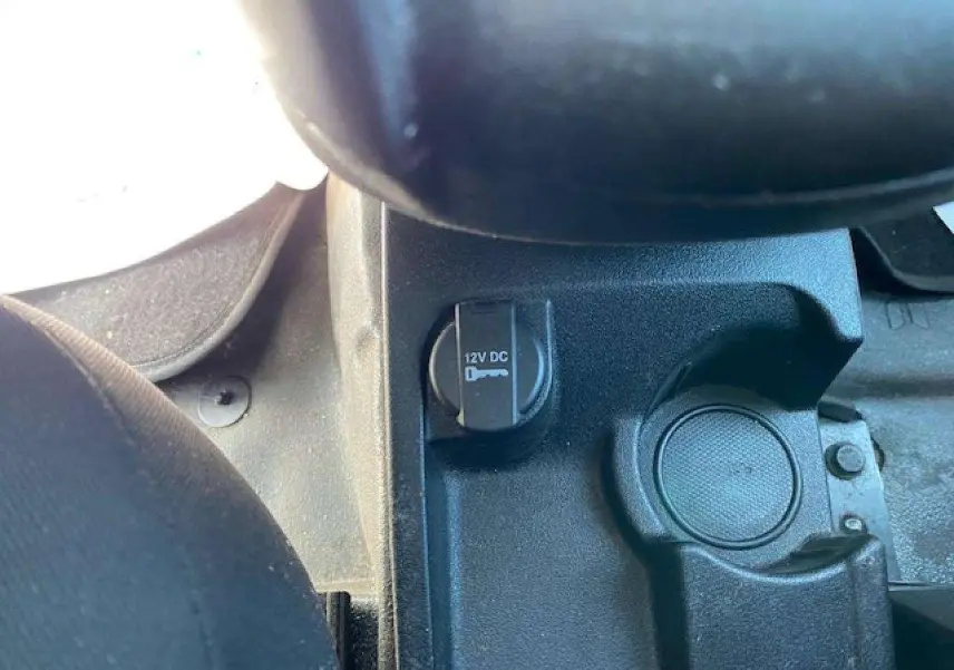 Vue rapprochée de la prise 12V et porte-gobelet dans l'habitacle du Fiat Doblo blanc de 2017.