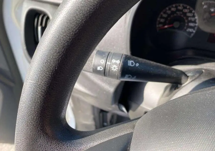Gros plan sur le volant et la commande des phares du Fiat Doblo 2017, intérieur en plastique noir texturé.