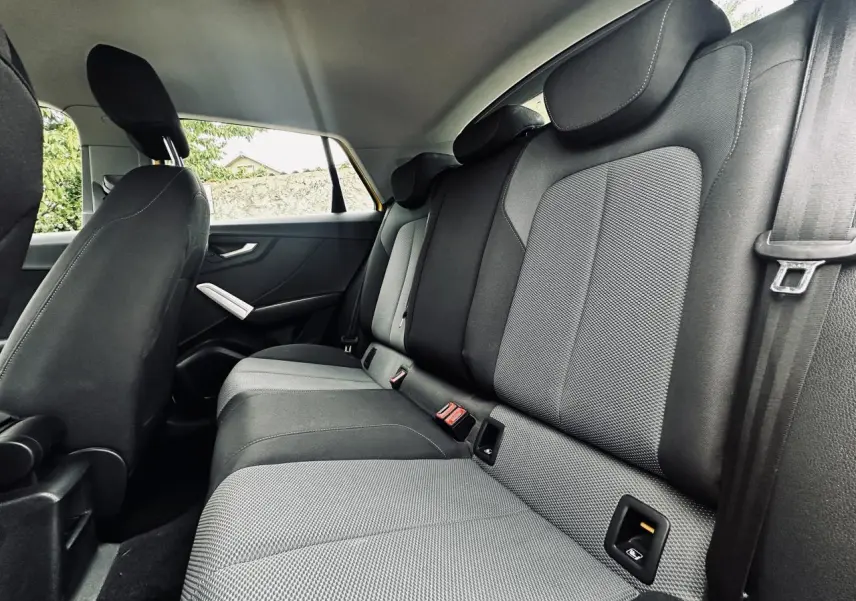 Vue latérale intérieure montrant les sièges arrière gris et noirs de l'Audi Q2 1.6 TDI Business line jaune.