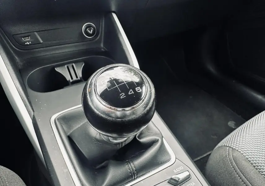 Gros plan sur le levier de vitesses manuel noir de l'Audi Q2, avec console centrale et siège tissu gris visibles.