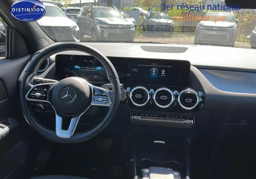 Vue intérieure avant du tableau de bord noir du Mercedes GLA 200 2022 avec volant cuir multifonction et écran tactile large.
