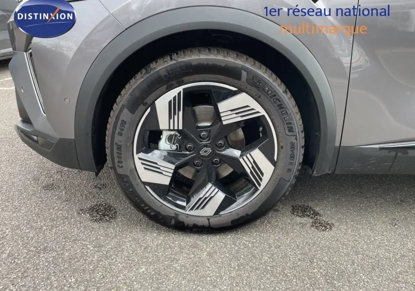 Gros plan sur la roue avant gauche d'une Renault Symbioz gris cassiopée métal, mettant en valeur la jante stylisée bicolore.
