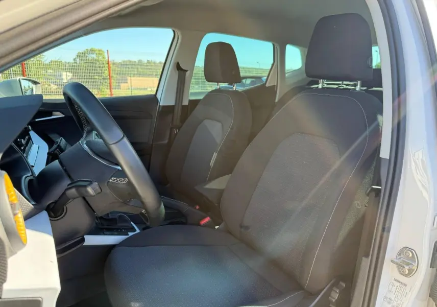 Vue intérieure côté conducteur du SEAT Arona 2025, sièges tissu gris Como et volant cuir multifonction.