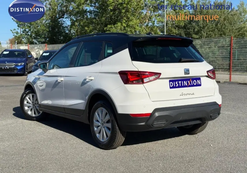 Vue 3/4 arrière droite d'un SEAT Arona blanc Candy avec toit noir Minuit, jantes alu et feux arrière LED.
