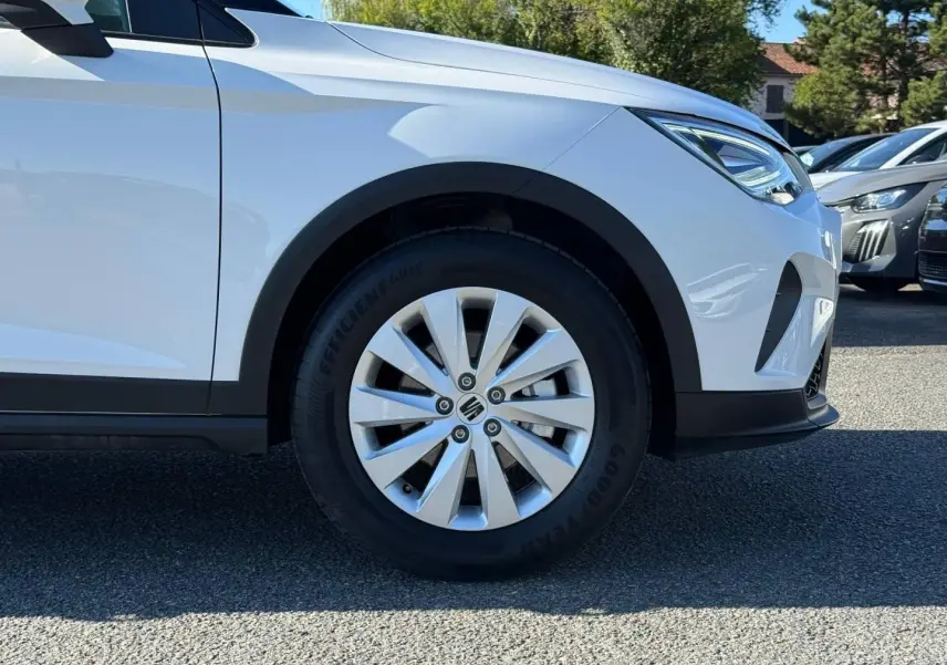 Gros plan sur la roue avant droite d’un SEAT Arona blanc Candy avec jante alu et détails noirs au pare-chocs.