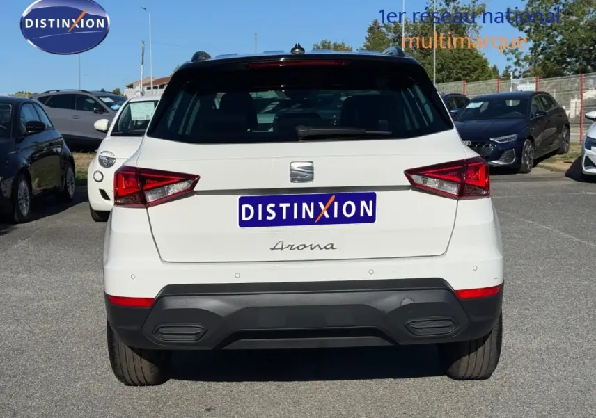 Vue arrière d'un SEAT Arona blanc Candy avec toit noir Minuit, stationné en extérieur sur un parking.