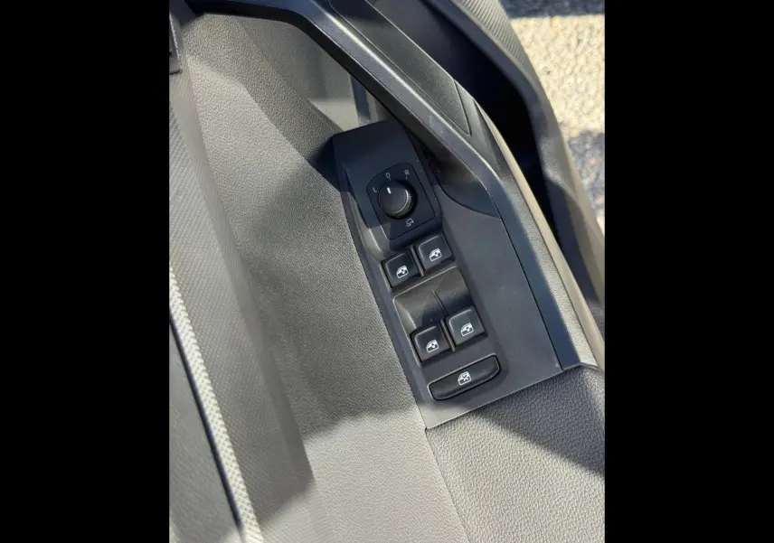Gros plan sur la commande des vitres et réglage des rétroviseurs côté conducteur, intérieur gris du SEAT Arona 2025.