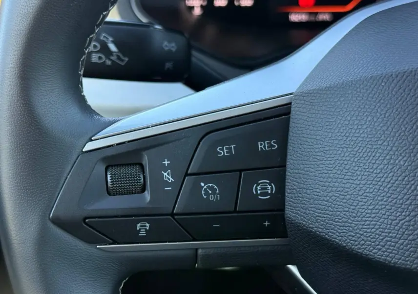 Gros plan sur les commandes de régulateur de vitesse au volant cuir noir du SEAT Arona 2025.