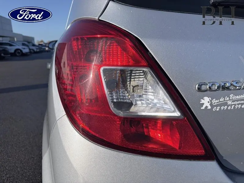 Gros plan sur le feu arrière droit gris minéral d'une Opel Corsa 2014 avec logo et badge visibles.