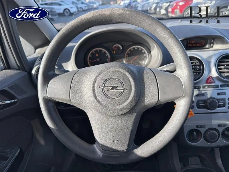 Vue rapprochée du volant noir avec logo Opel au centre, tableau de bord gris et commandes de climatisation visibles.