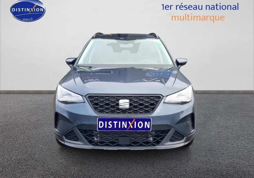 Vue avant d'un SEAT Arona gris magnétique avec calandre noire et projecteurs full LED allumés.