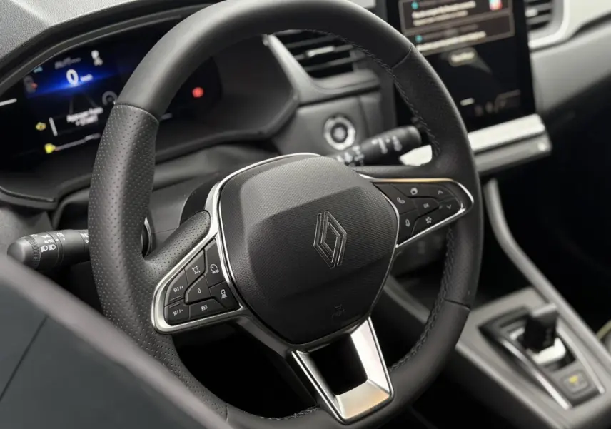 Vue rapprochée du volant noir perforé du Renault Captur 2025 avec commandes intégrées et tableau de bord numérique.