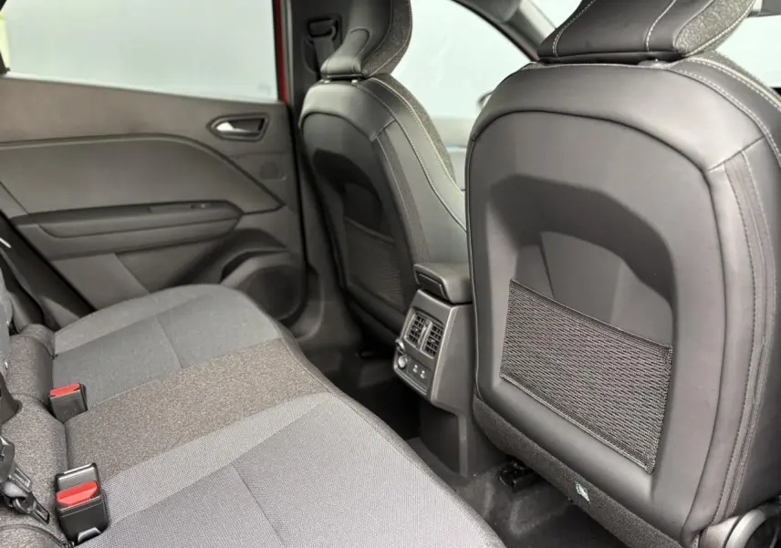 Vue arrière intérieure du Renault Captur 2025, montrant les sièges arrière gris et les aérations centrales.