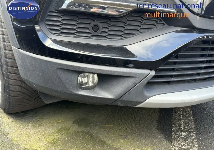 Gros plan sur le pare-chocs avant droit noir de l'Opel Grandland X avec antibrouillard et calandre hexagonale.