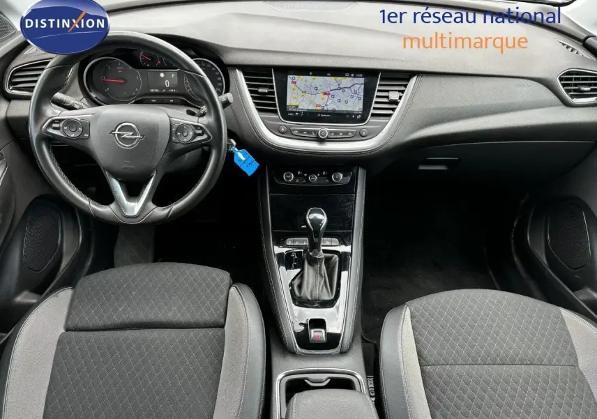 Vue intérieure avant de l’Opel Grandland X noir, montrant le tableau de bord, volant multifonction et console centrale avec boîte automatique.