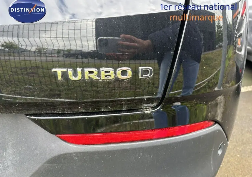 Gros plan sur l'arrière noir d'un Opel Grandland X 1.5D avec l'inscription Turbo D et un feu arrière rouge visible.