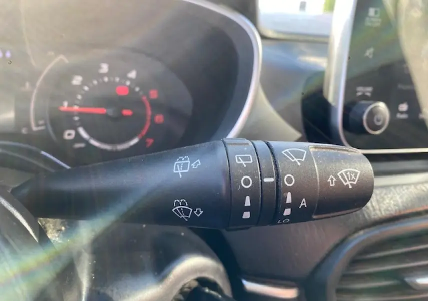 Gros plan sur la commande des essuie-glaces dans l’habitacle du Fiat Tipo bleu, avec tableau de bord flou en arrière-plan.
