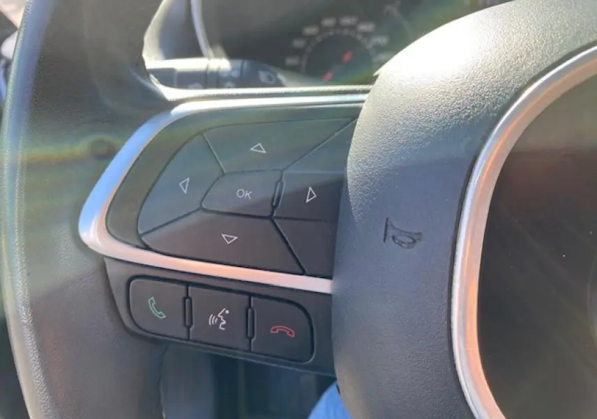 Gros plan sur les commandes au volant côté gauche du Fiat Tipo 2018, avec boutons de navigation et téléphone.