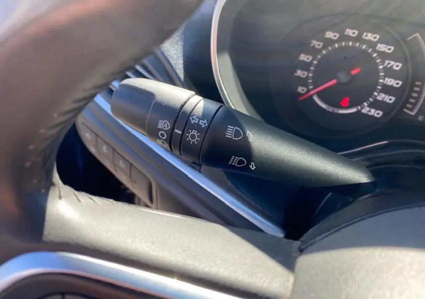 Gros plan sur la manette des feux et clignotants à gauche du volant dans l’habitacle du Fiat Tipo bleu 2018.