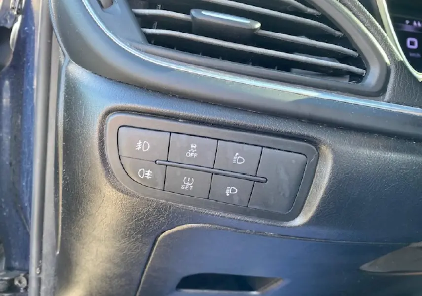 Gros plan sur les commandes d’éclairage et d’aide à la conduite sur la planche de bord noire du Fiat Tipo bleu 2018.
