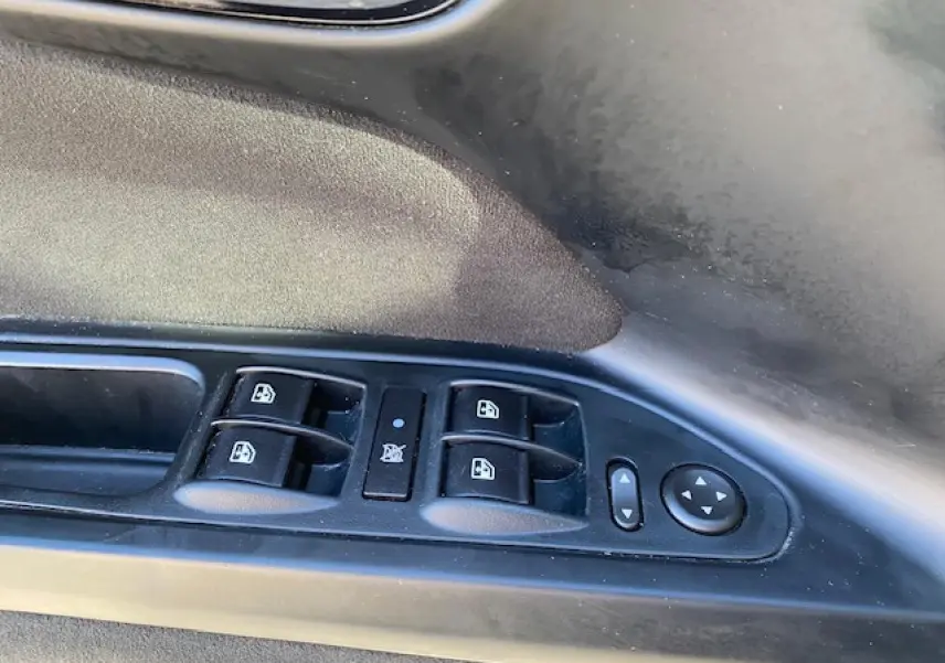 Gros plan sur les commandes des vitres électriques et réglage des rétroviseurs côté conducteur d'une Fiat Tipo bleue.