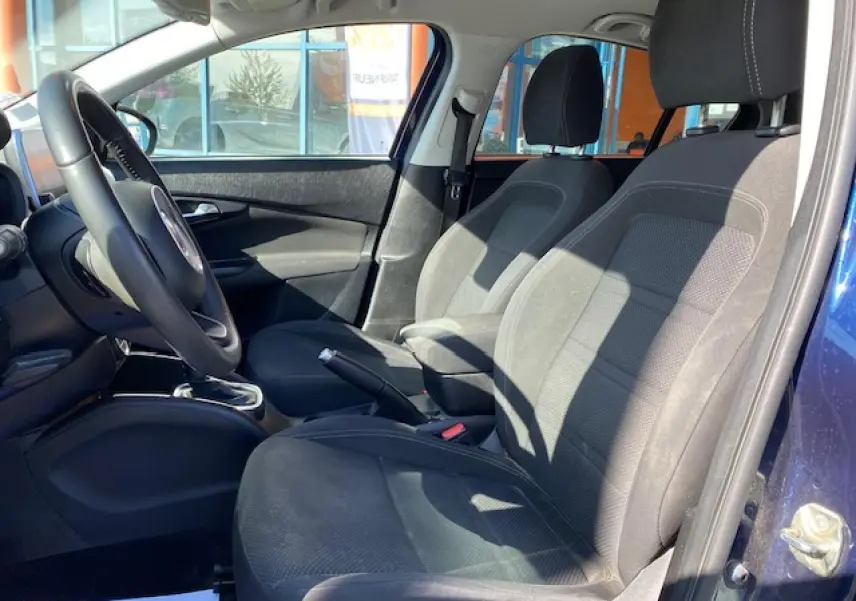 Vue intérieure côté conducteur de la Fiat Tipo bleu 2018, mettant en valeur les sièges tissu noirs et le volant.
