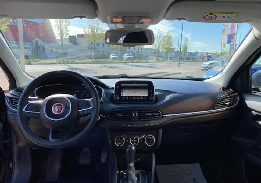 Vue intérieure avant du Fiat Tipo 2018 bleu, montrant le volant, l’écran tactile central et la console avec boîte automatique.