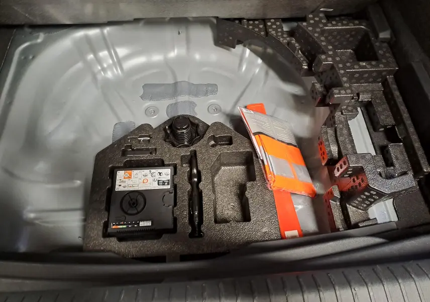Vue rapprochée du coffre ouvert d'une CUPRA Formentor 2025, montrant le rangement sous plancher gris avec kit de secours.