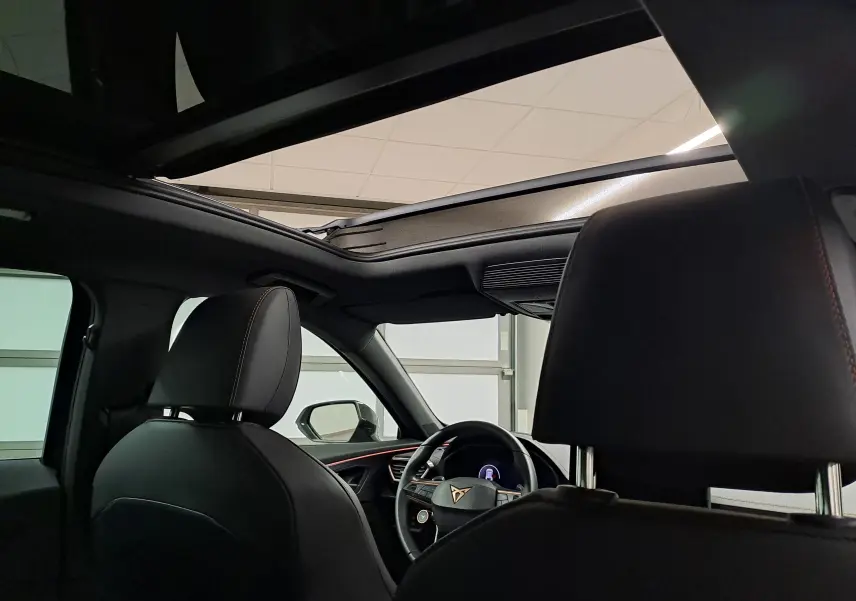 Vue intérieure du CUPRA Formentor 2025 montrant le toit ouvrant panoramique et les sièges en cuir noir avec surpiqûres cuivrées.