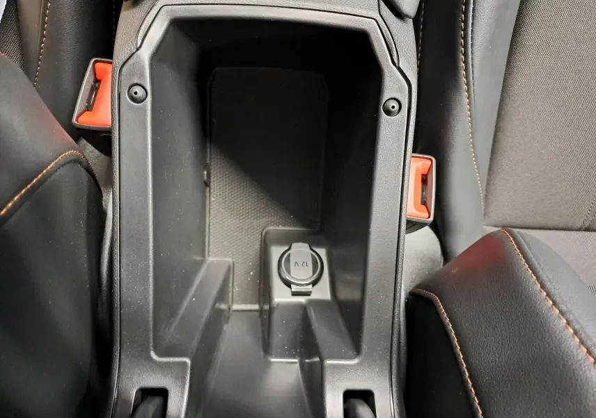 Vue rapprochée de la console centrale intérieure noire avec prise 12V et surpiqûres cuivrées des sièges CUPRA Formentor.