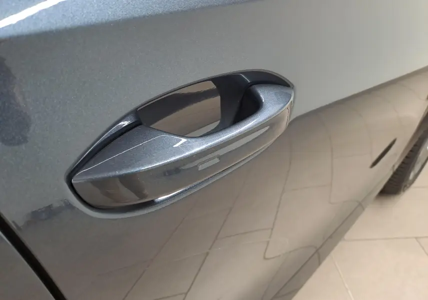 Poignée de porte côté droit en gros plan sur CUPRA Formentor gris magnétique avec reflet du sol carrelé.