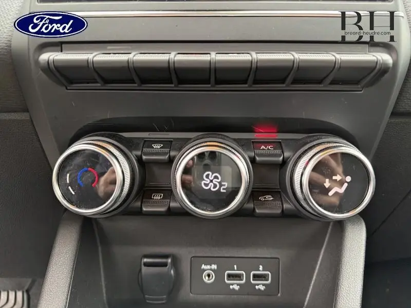Détail des commandes de climatisation avec trois molettes et ports USB, intérieur d’un véhicule Ford.