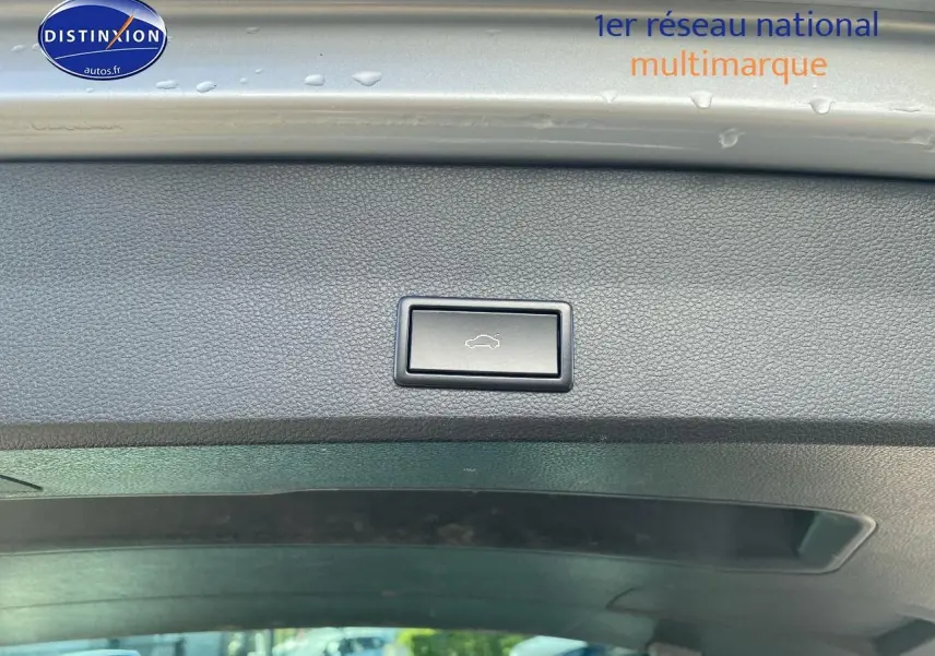 Bouton d'ouverture électrique du hayon sur le bord intérieur du coffre d'un SEAT Ateca gris, vue intérieure arrière.