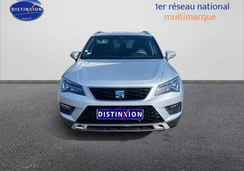 Vue frontale d'un SEAT Ateca gris 2020 avec calandre noire et phares LED distinctifs allumés.
